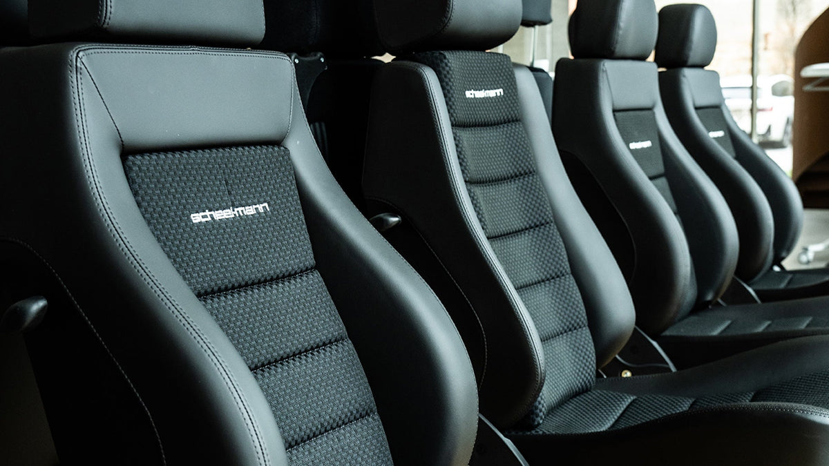Row of black scheel-mann seats with leather bolsters and basketweave cloth centers, each embroidered with the scheel-mann logo