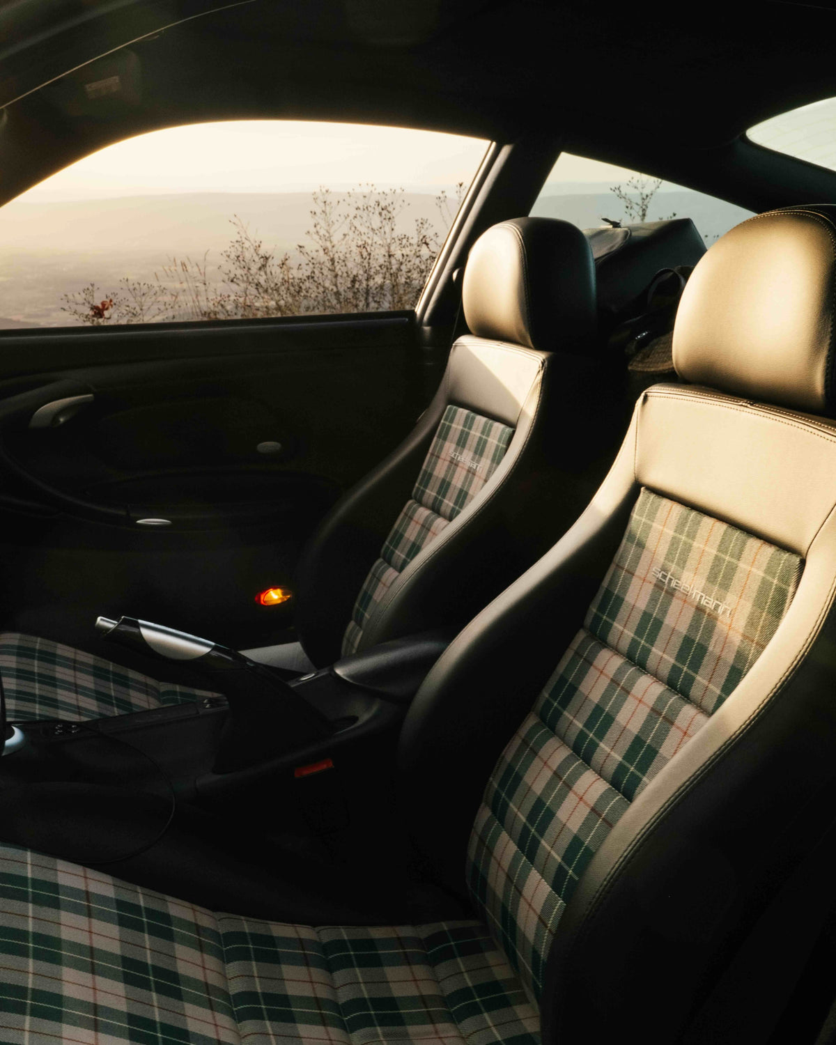 black Sportline scheel-mann seats with green plaid center fabric in a Porsche 996, looking at the fronts seats through driver door