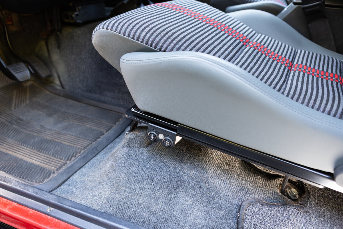 Dual switch mount installed on a driver seat mounted on the left side of the seat bracket, showing bottom cushion and left bolster in gray