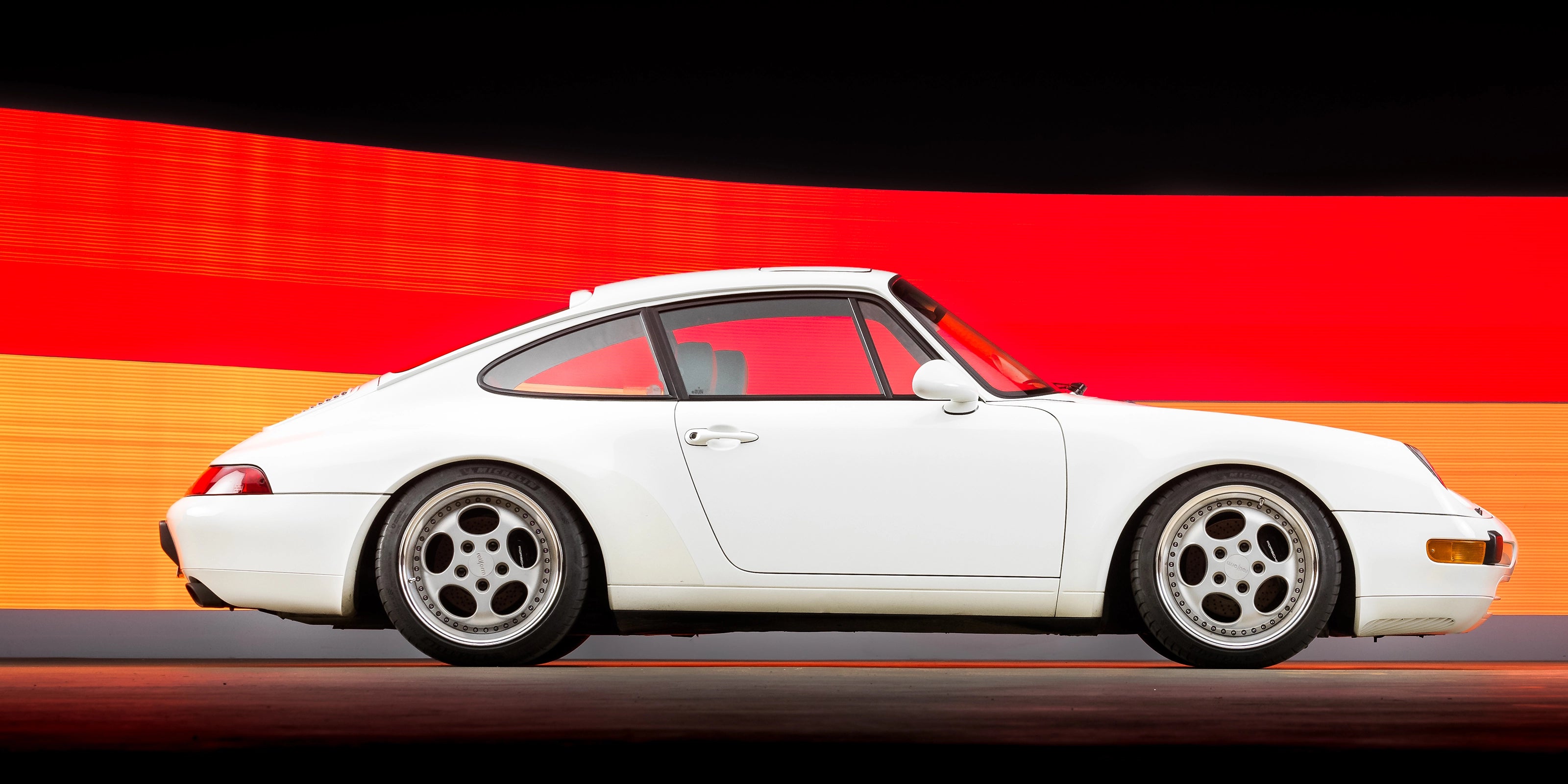 Porsche 993 with Rotiform STR Wheels, riding on KW coilovers, in front of a German flag light installation by photographer Josh Bryan of The Image Engine.