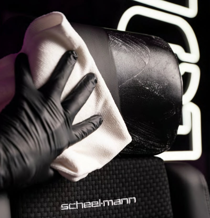 Gloved hand wiping a scheel-mann headrest with a white microfiber cloth